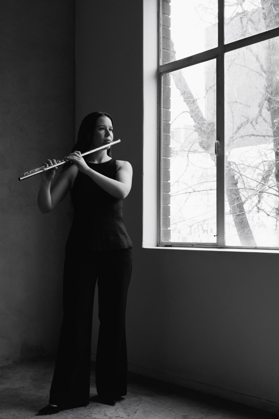 Lauren playing the flute by a large window
